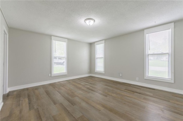 empty room with baseboards, a textured ceiling, and wood finished floors