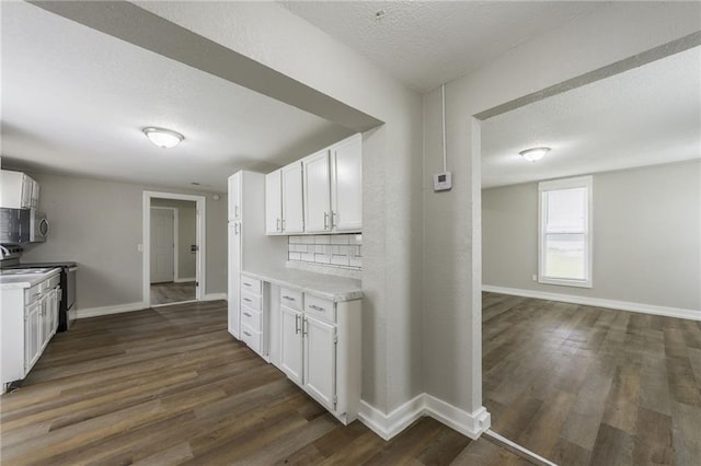 kitchen featuring range with electric cooktop, a textured ceiling, light countertops, white cabinets, and stainless steel microwave