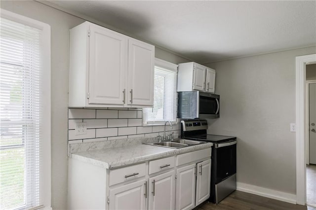 kitchen featuring backsplash, dark wood finished floors, a sink, white cabinets, and stainless steel appliances