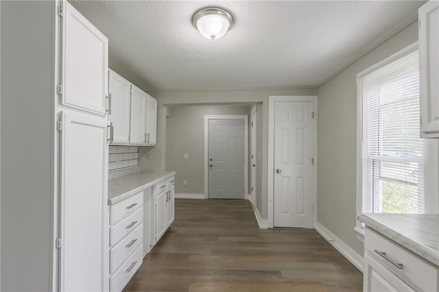 kitchen with light countertops, a textured ceiling, white cabinetry, baseboards, and wood finished floors