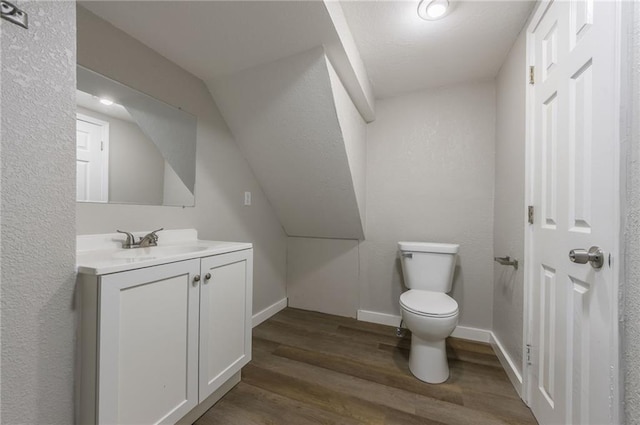 half bathroom featuring toilet, baseboards, wood finished floors, and vanity