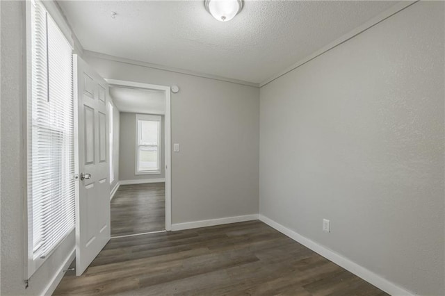 unfurnished room with baseboards, dark wood-style floors, and a textured ceiling