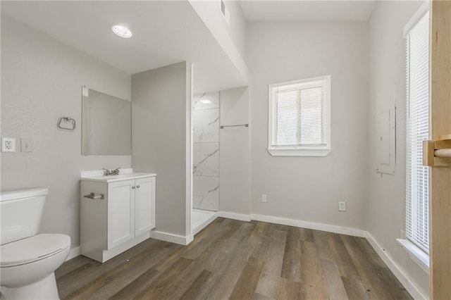 bathroom with a stall shower, wood finished floors, vanity, baseboards, and toilet