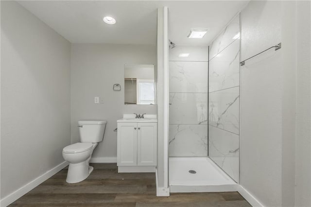 bathroom with vanity, toilet, a marble finish shower, baseboards, and wood finished floors