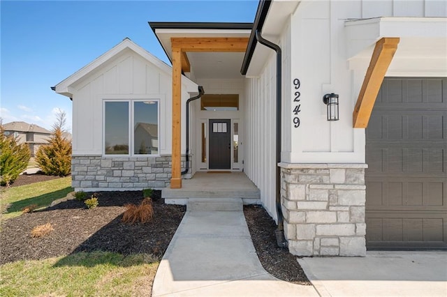 property entrance featuring board and batten siding, an attached garage, and stone siding