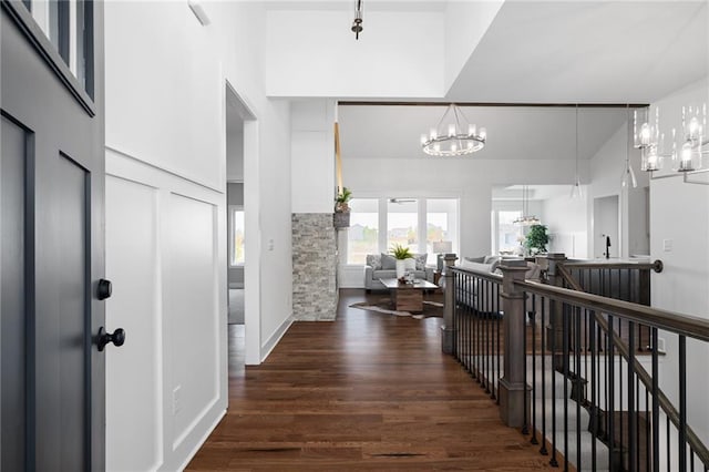 hallway featuring an inviting chandelier, wood finished floors, and an upstairs landing