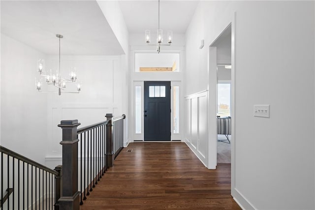 foyer with a decorative wall, wood finished floors, and a notable chandelier