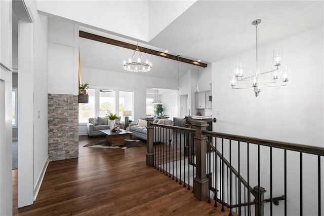 hall featuring an inviting chandelier, an upstairs landing, wood finished floors, and a towering ceiling