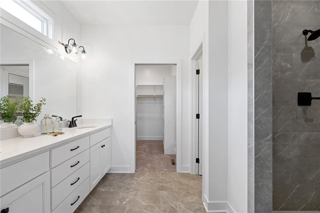 full bath featuring walk in shower, vanity, marble finish floor, baseboards, and a spacious closet