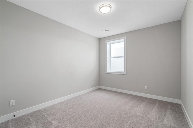 unfurnished room featuring baseboards, visible vents, and light colored carpet