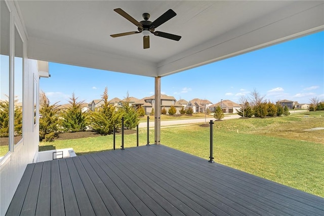 wooden deck featuring a lawn, a ceiling fan, and a residential view