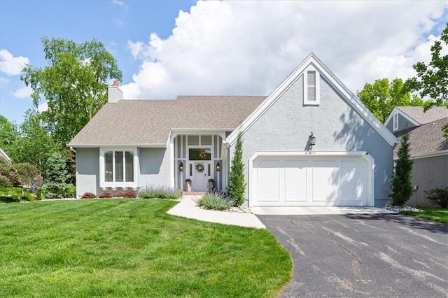view of front of home with driveway, an attached garage, a front yard, a chimney, and stucco siding
