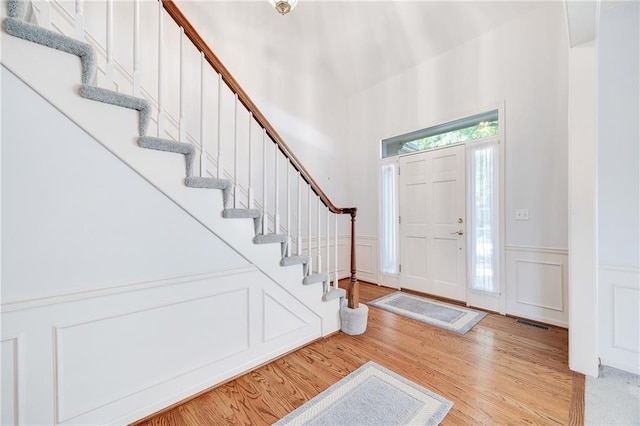 2269 SW Park Ave, Blue Springs, MO 64015 - foyer featuring stairway, light wood-style floors, a decorative wall, a wainscoted wall, and a high ceiling