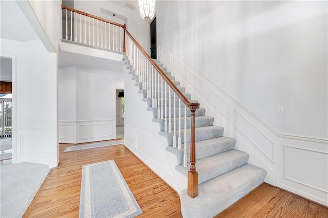 2269 SW Park Ave, Blue Springs, MO 64015 - staircase with a decorative wall, wood finished floors, a towering ceiling, and wainscoting