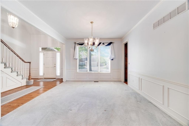 2269 SW Park Ave, Blue Springs, MO 64015 - unfurnished dining area featuring carpet floors, a chandelier, a decorative wall, a wainscoted wall, and stairway