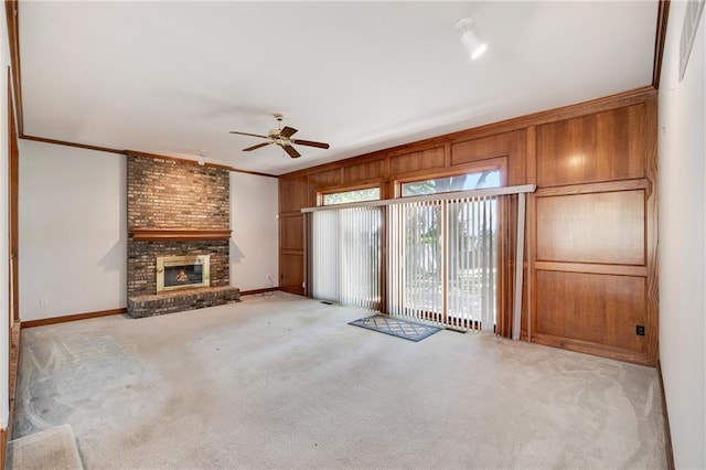 2269 SW Park Ave, Blue Springs, MO 64015 - unfurnished living room with a ceiling fan, ornamental molding, light carpet, a fireplace, and wooden walls
