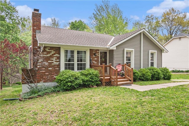 ranch-style house featuring roof with shingles, a wooden deck, a chimney, and a front yard
