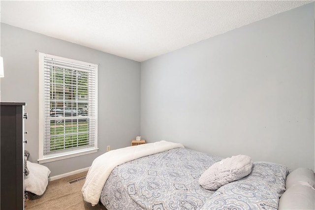 carpeted bedroom with a textured ceiling, baseboards, and visible vents