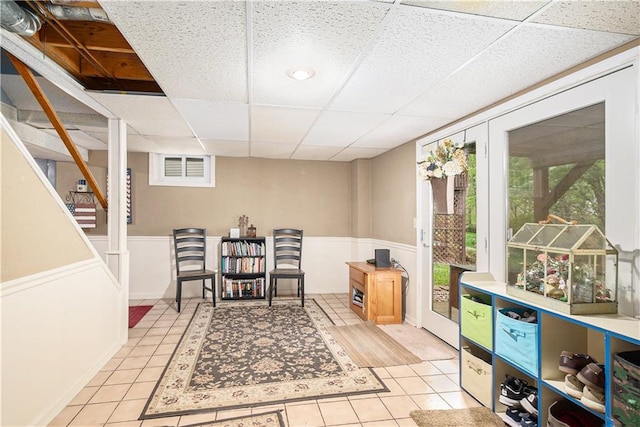 living area with a paneled ceiling, light tile patterned flooring, and a wealth of natural light