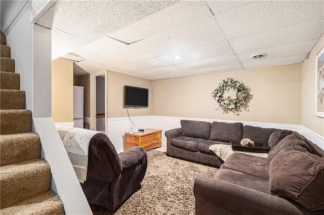 carpeted living area featuring stairs, visible vents, and a paneled ceiling