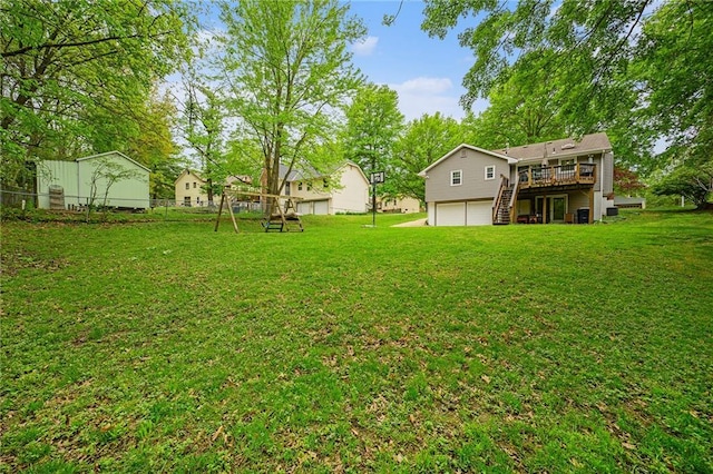 view of yard featuring a garage, fence, a wooden deck, and stairway