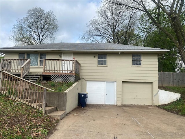 back of house featuring a deck, stairway, fence, a garage, and driveway