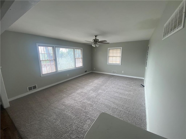 carpeted empty room featuring visible vents, ceiling fan, and baseboards