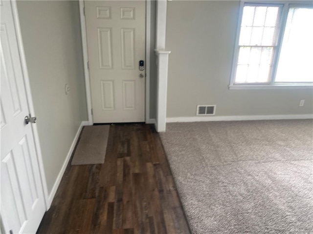 interior space with dark wood-type flooring, visible vents, and baseboards