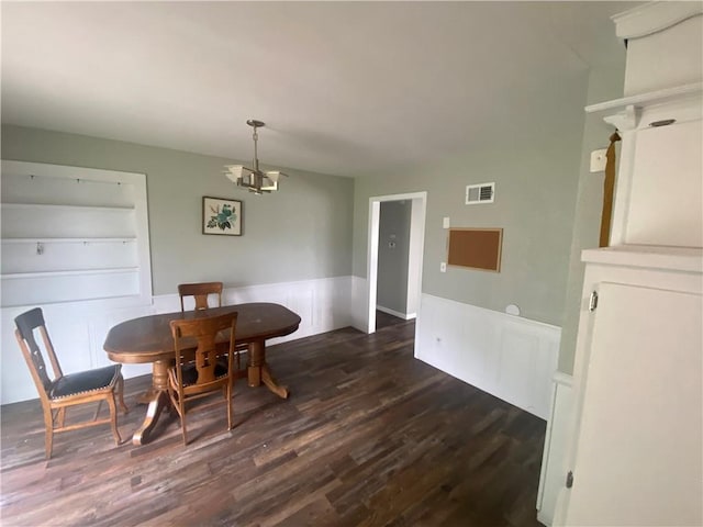 dining area with a chandelier, visible vents, dark wood finished floors, and wainscoting