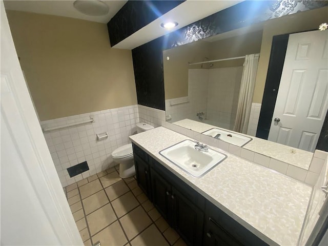 bathroom with tile patterned flooring, tile walls, a wainscoted wall, toilet, and curtained shower