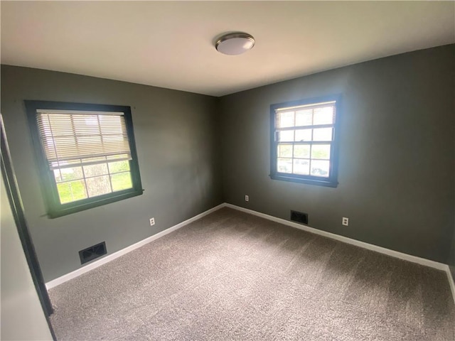 spare room with visible vents, a healthy amount of sunlight, carpet flooring, and baseboards