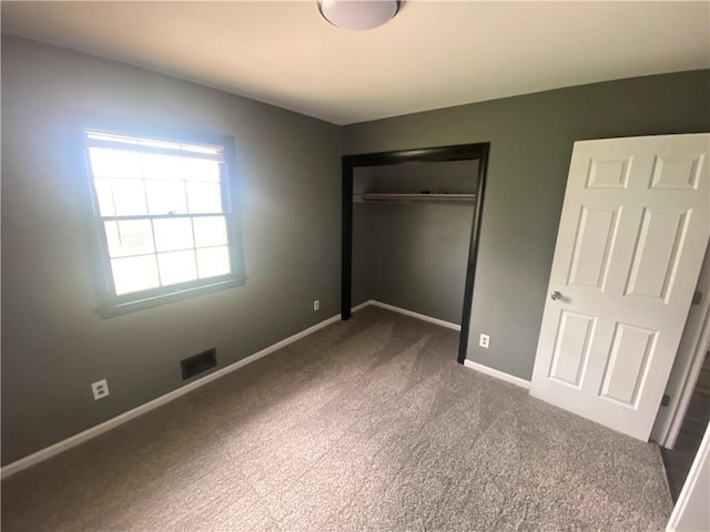 unfurnished bedroom with a closet, visible vents, carpet, and baseboards