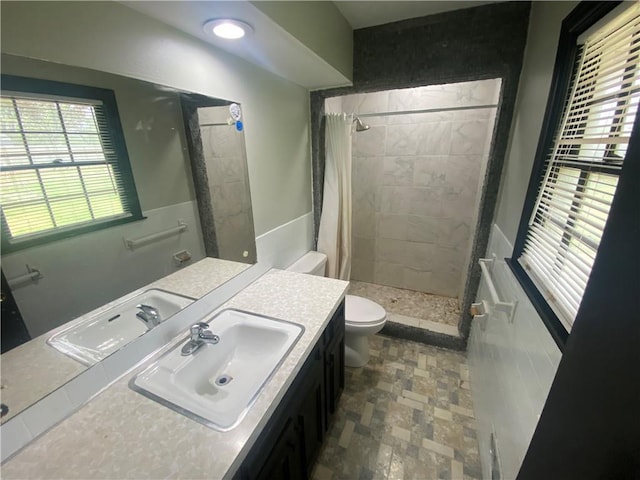 bathroom with toilet, vanity, a shower stall, and stone finish flooring