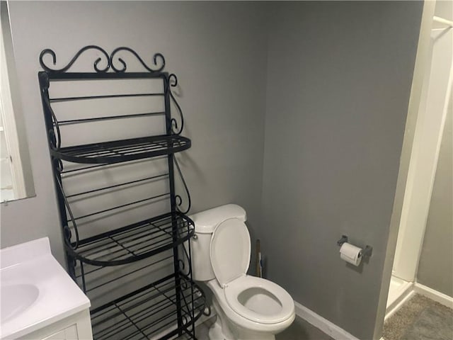 bathroom featuring baseboards, walk in shower, toilet, and vanity
