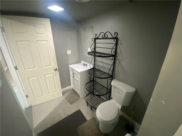 bathroom with toilet, vanity, and baseboards