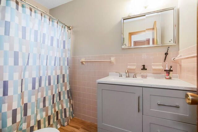 1835 Miami St, Leavenworth, KS 66048 - bathroom featuring tile walls, vanity, wood finished floors, wainscoting, and a shower with shower curtain