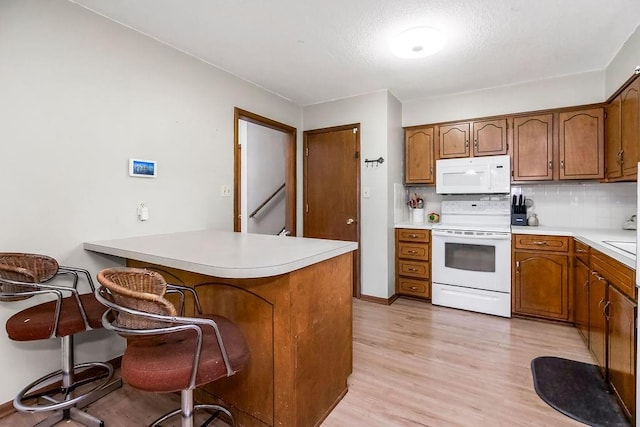 1835 Miami St, Leavenworth, KS 66048 - kitchen featuring white appliances, brown cabinets, a peninsula, and light wood-style flooring