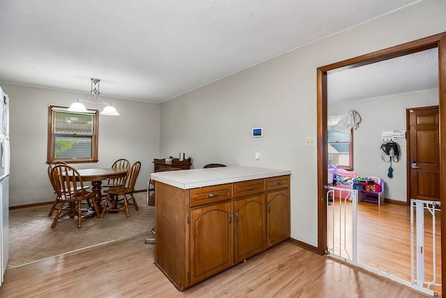 1835 Miami St, Leavenworth, KS 66048 - kitchen with a peninsula, light wood finished floors, light countertops, brown cabinets, and hanging light fixtures