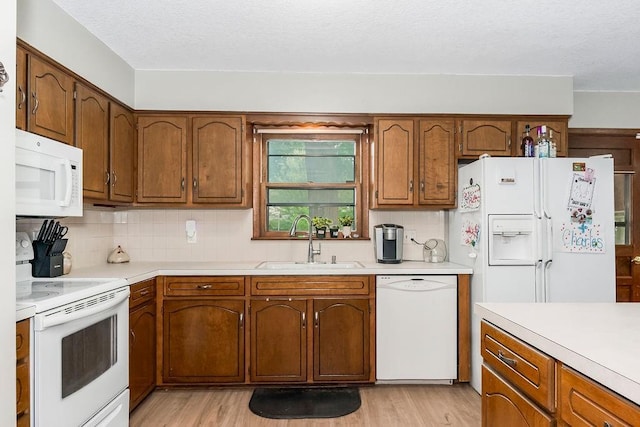 1835 Miami St, Leavenworth, KS 66048 - kitchen featuring white appliances, light wood-style flooring, light countertops, backsplash, and a textured ceiling