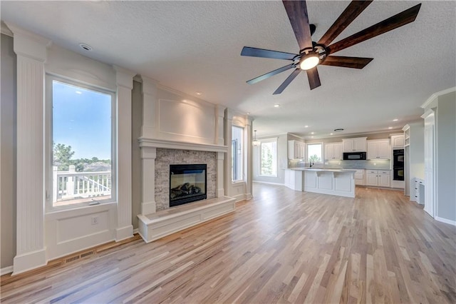 24108 W 67th Ter, Shawnee, KS 66226 - unfurnished living room with a textured ceiling, a stone fireplace, light wood-type flooring, a ceiling fan, and recessed lighting