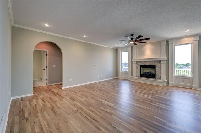 24108 W 67th Ter, Shawnee, KS 66226 - unfurnished living room with a textured ceiling, a ceiling fan, crown molding, light wood-type flooring, and arched walkways