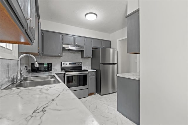 kitchen with a sink, gray cabinets, stainless steel appliances, tasteful backsplash, and under cabinet range hood