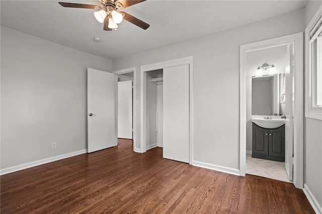 unfurnished bedroom with a sink, ensuite bath, baseboards, wood finished floors, and a closet