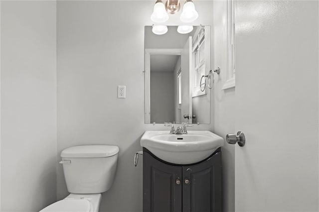 bathroom with an inviting chandelier, vanity, and toilet