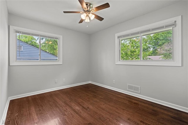 spare room with dark wood-style flooring, baseboards, visible vents, and ceiling fan