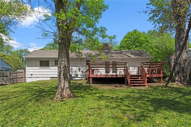 back of property with fence, a lawn, and a deck