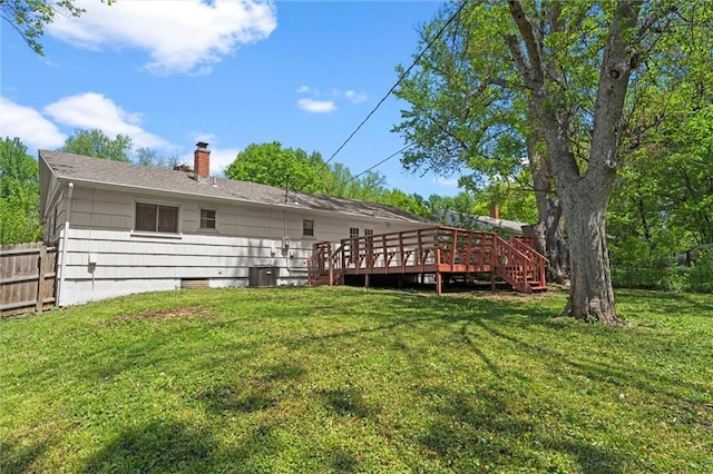 rear view of property featuring fence, a chimney, a lawn, and a deck