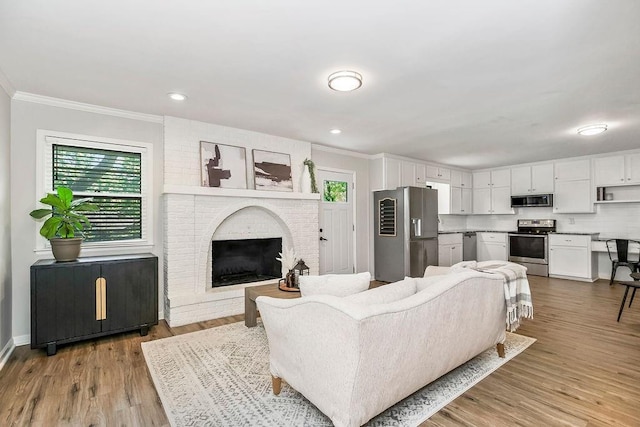 2427 N 83rd Ln, Kansas City, KS 66109 - living room featuring crown molding, a brick fireplace, wood finished floors, recessed lighting, and baseboards