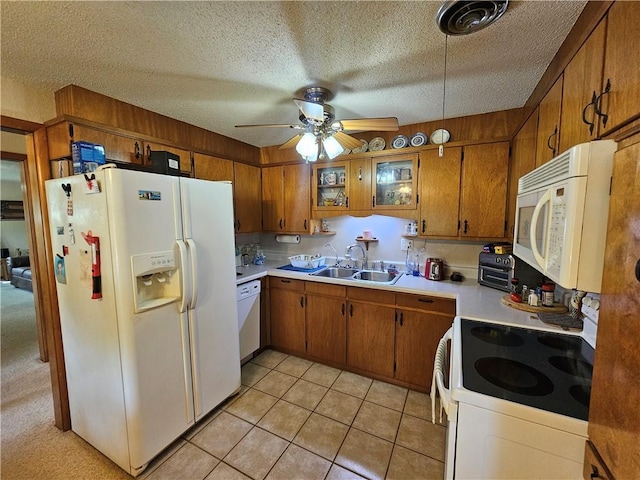 kitchen featuring light countertops, a sink, brown cabinets, and white appliances
