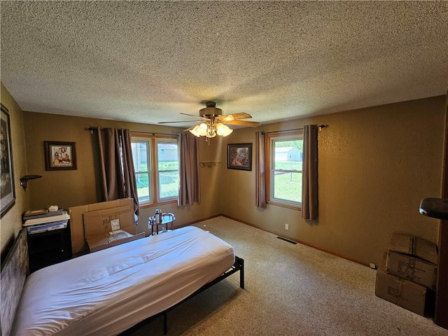 bedroom with carpet flooring, a textured ceiling, visible vents, and ceiling fan